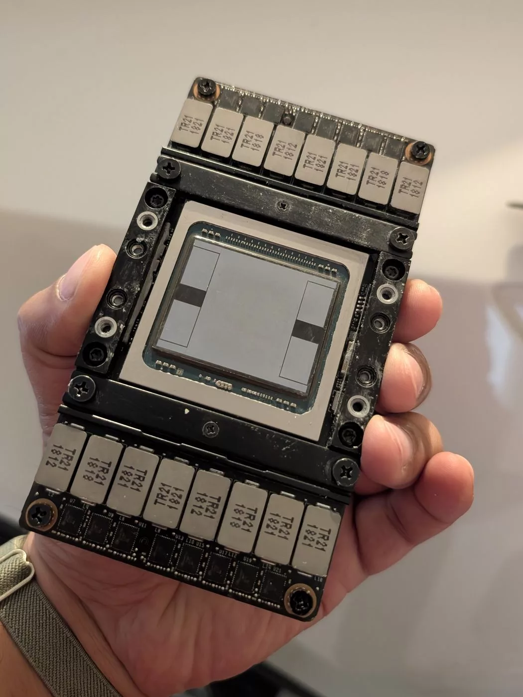 A bare Tesla V100 SXM2 module held in one hand